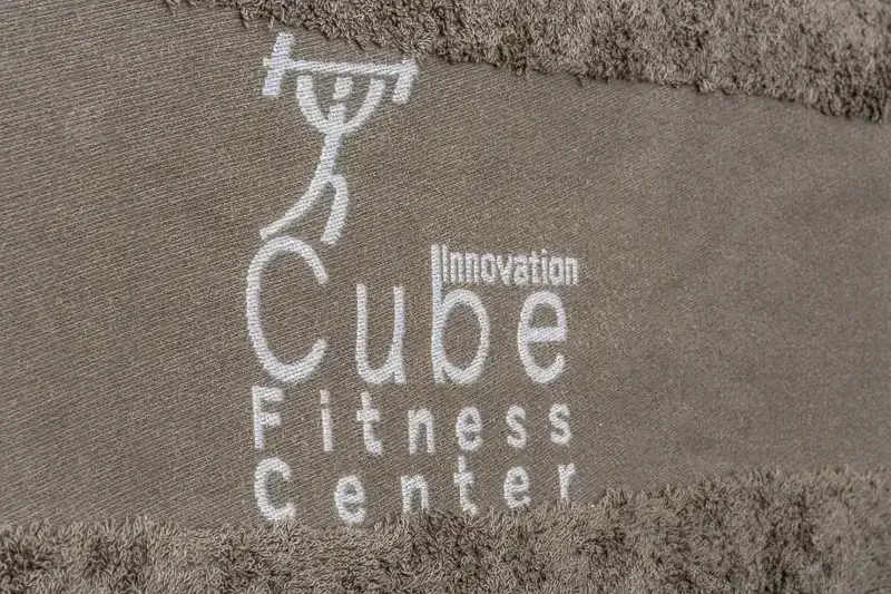 Vytkávané logo fitness centra na okraji športového uteráka